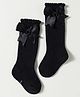 Cute Walk by Babyhug Non Terry Knit Calf Length Solid Party Socks with Bow Applique & Cable Knit Design - Black